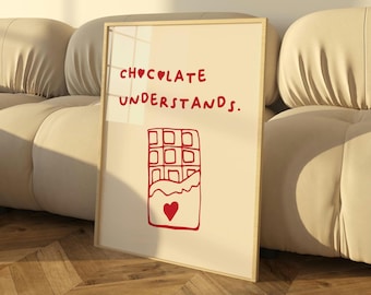 May include: A white framed print with red text that reads "CHOCOLATE UNDERSTANDS."  A red illustration of a chocolate bar with a heart in the center is below the text.