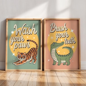 Op de afbeelding: Twee ingelijste kunstprints. Eén toont een tijger met de tekst "Wash your paws" en de andere een alligator met de tekst "Brush your teeth". Beide prints hebben een retro-ontwerp met een gele cirkelachtergrond en steraccenten.