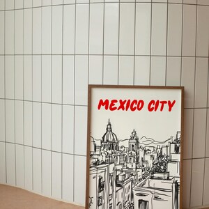 May include: A framed black and white line drawing of the Mexico City skyline with the text "MEXICO CITY" in red letters at the top of the frame.