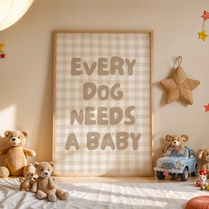 Op de afbeelding: Een kinderkamer met een ingelijste print met de tekst "EVERY DOG NEEDS A BABY". De kamer is ingericht met teddyberen, stervormige wanddecoraties en een speelgoedauto. Het kleurenschema is neutraal met beige en bruine tinten.