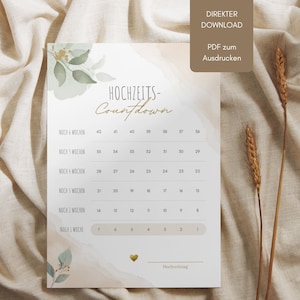 Puede incluir: Un gráfico de cuenta atrás para bodas imprimible con un fondo de acuarela y detalles dorados. El gráfico incluye el texto "Hochzeits-Countdown" y enumera el número de semanas hasta el día de la boda.