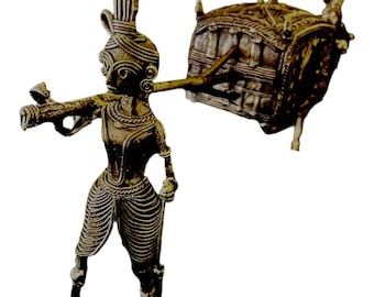 May include: A gold-colored metal sculpture of a person carrying a palanquin. The sculpture is detailed with intricate patterns and designs.
