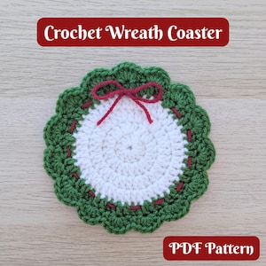 May include: A handmade crochet coaster in a wreath design. The coaster features a white center, a green outer ring, and a red bow. The text "Crochet Wreath Coaster" and "PDF Pattern" are displayed on the image.
