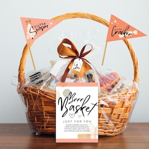 May include: A wicker gift basket filled with treats, tied with a brown ribbon and a tag that says "Just for You." The basket has two decorative flags that read "Tis the Season" and "You're a Cracker." A card in front says "Brrr Basket."