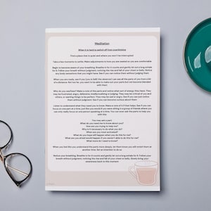 May include: A printed page with the title "Meditation" and text about mindfulness, next to a teal saucer with a cup of coffee and a pair of round-framed glasses. The page has a light beige border.