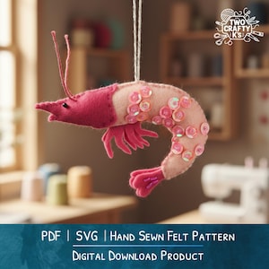 May include: A handmade felt shrimp ornament in shades of pink and peach, embellished with sequins. The shrimp has a detailed design with a pink head, tail, and legs. The text at the bottom reads "PDF | SVG | HAND SEWN FELT PATTERN DIGITAL DOWNLOAD PRODUCT."