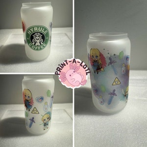 May include: Three frosted glass tumblers with different designs. The first tumbler has a green logo that says "Hyrule Coffee". The second tumbler has a watercolor design with a character from the Legend of Zelda video game series. The third tumbler has a similar watercolor design with two characters from the Legend of Zelda video game series.