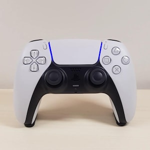 May include: A white and black wireless video game controller featuring a central touchpad with a glowing blue light bar, two black analogue sticks, a directional pad, and four action buttons with silver circular icons on the right side.