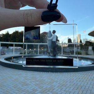 Könnte beinhalten: Transparenter Acryl-Schlüsselanhänger mit schwarzem Clip. Der Schlüsselanhänger hat ein kleines Bild einer Person und eines tanzenden Paares. Der Text auf dem Schlüsselanhänger lautet "Was that the bite of 87?!"