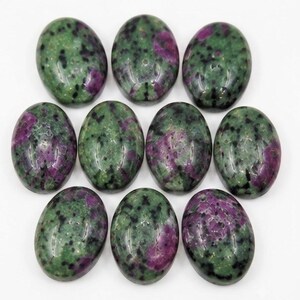 Peut inclure: Dix cabochons de forme ovale en zoïsite avec des inclusions de rubis. Chaque pierre présente une surface polie et lisse affichant un motif marbré de vert forêt profond, de magenta vibrant et de petites taches noires sur tout le matériau.