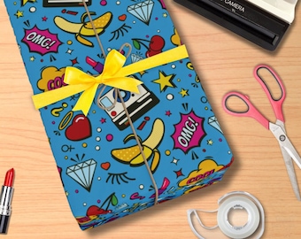 May include: A blue gift wrap with a colorful pattern of hearts, stars, cherries, bananas, cameras, and the word "OMG!" repeated. The gift wrap is tied with a yellow ribbon.