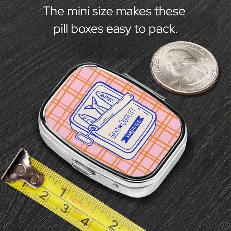 Peut inclure: Petite bo&icirc;te &agrave; pilules rectangulaire avec un motif de bo&icirc;te de sardines sur le couvercle. Le couvercle pr&eacute;sente un motif &agrave; carreaux roses et une illustration de bo&icirc;te de sardines bleue et blanche. Le texte "BEST QUALITY SARDINES" est visible.