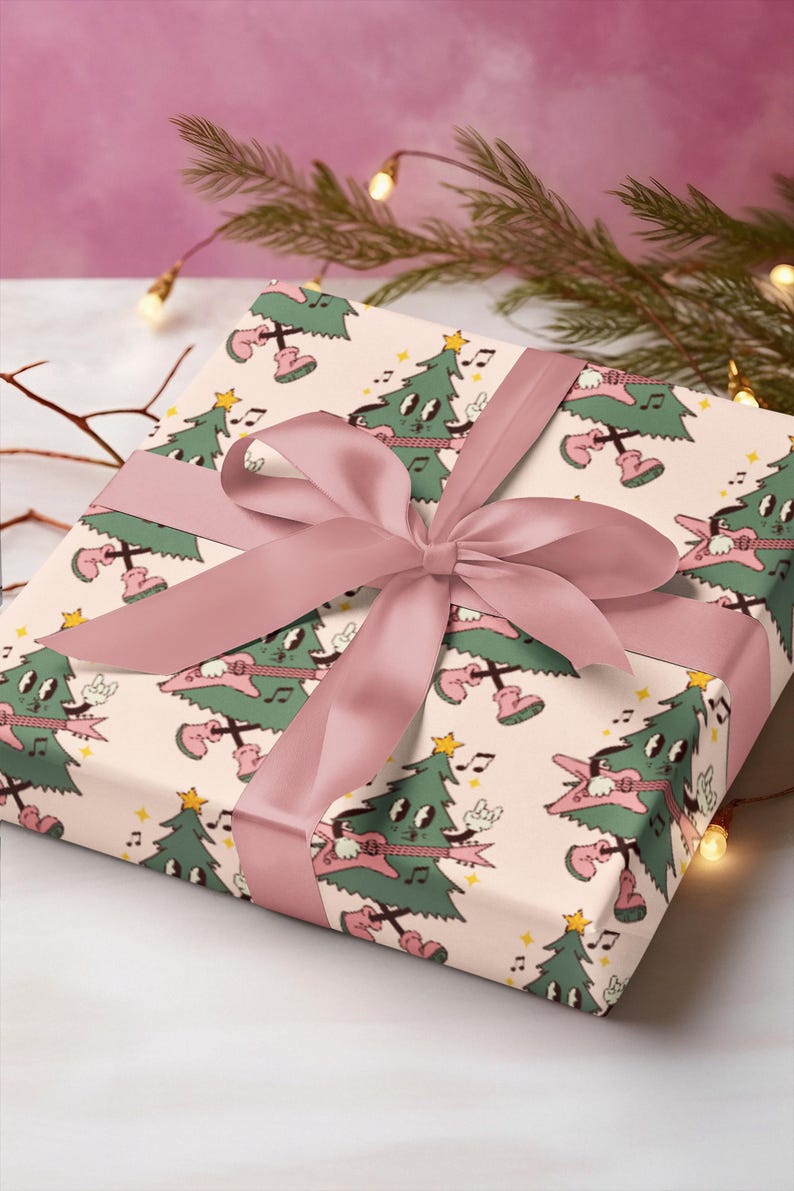 May include: A pink gift box with a white background and a pattern of green Christmas trees playing electric guitars. The box is tied with a pink satin ribbon.