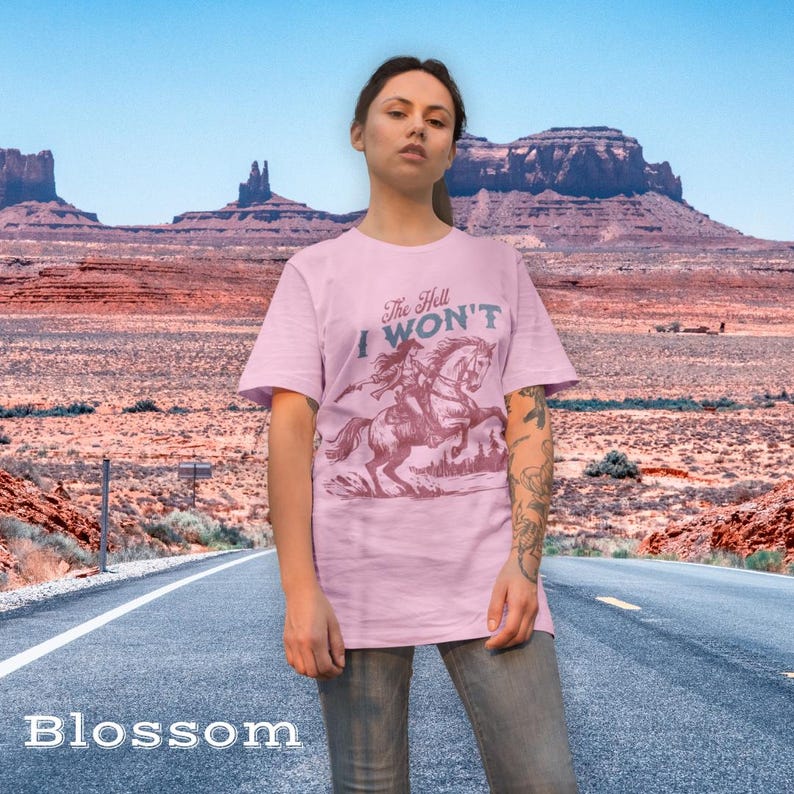 May include: A pink t-shirt with a graphic of a woman riding a horse. The text on the shirt reads "The Hell I Won't".