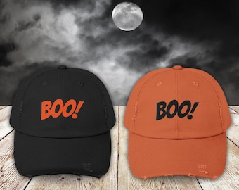 Op de afbeelding: Twee baseballpetten met het woord "BOO!" in oranje letters. De ene pet is zwart en de andere is oranje.