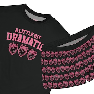 May include: Black pajama set with a pink strawberry print. The top features the text "A Little Bit Dramatic" in pink letters.