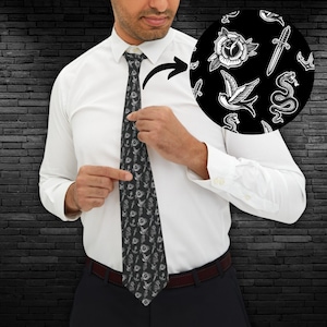 Könnte beinhalten: Eine schwarze Krawatte mit einem weißen Muster aus verschiedenen Tattoo-artigen Bildern, darunter eine Rose, ein Dolch, eine Schlange und ein Vogel.