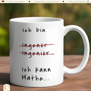 Op de afbeelding: Witte keramische mok met zwarte tekst die "Ich bin Ingenör Ingenior Ich kann Mathe..." luidt. De woorden "Ingenör" en "Ingenior" zijn doorstreept met rode lijnen.