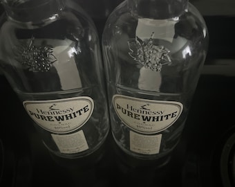 Könnte beinhalten: Zwei klare Glasflaschen Hennessy Pure White Cognac, jede mit einem Etikett mit der Aufschrift "Hennessy Pure White Cognac 40%vol".