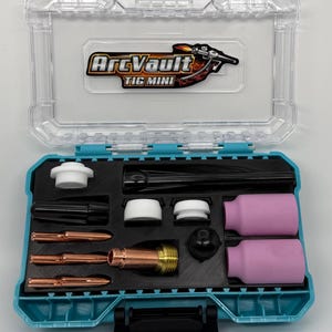 May include: An open, clear plastic case with a teal interior, containing welding equipment. The case has the text "ArcVault TIG MINI" on the lid. Inside are various components, including copper nozzles, pink cylinders, and black and white parts.