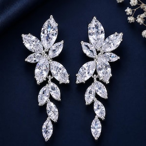 May include: A pair of silver-toned drop earrings featuring a cluster of marquise-cut clear cubic zirconia stones arranged in a floral and leaf-like pattern. The design consists of a larger top section and a dangling lower section of stones.