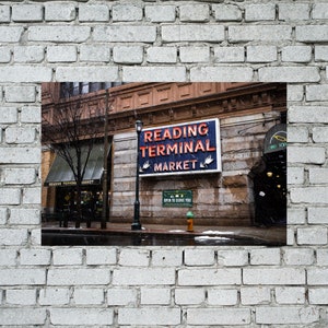 May include: A vintage sign with red neon lettering reads "Reading Terminal Market" on a brick building. The sign is above a doorway with a sign that reads "Twelfth Street".