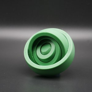 May include: A green wooden toy with concentric circles, resembling a sphere.