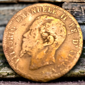 Puede incluir: Una moneda de color dorado con la inscripción "LUIS DE MANUEL I RE D", un perfil de rostro de hombre y un borde de cuentas.