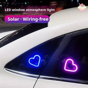 May include: A white car with two heart-shaped LED window lights. One light is blue, and the other is pink. The text "LED window atmosphere light" and "Solar • Wiring-free" is visible.