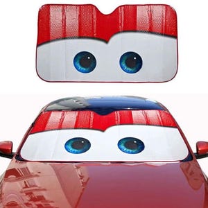 May include: A red and white car sunshade with a cartoon eye design. The sunshade has blue eyes and a red and white striped top. The sunshade is shown both separately and installed on a red car.