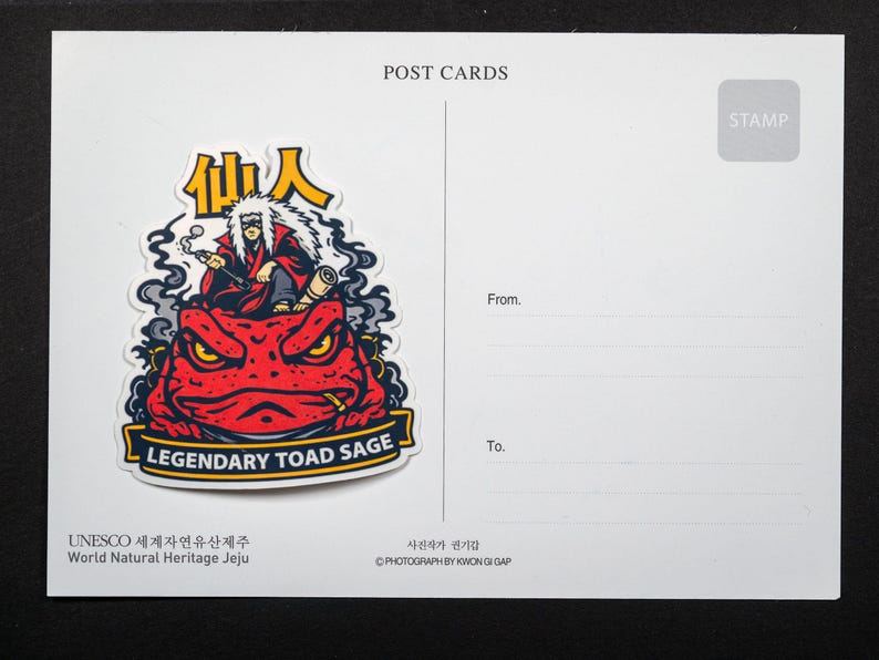 Puede incluir: Una postal con una pegatina de un personaje fumando en pipa, encima de un sapo rojo con el texto "LEGENDARY TOAD SAGE". La postal tiene l&iacute;neas para "De" y "Para", y el texto "POST CARDS".