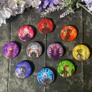 May include: Ten round, colorful, glass-like buttons with stained glass designs featuring various characters. Each button has a different color and character.