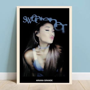 Puede incluir: Un póster con un retrato de primer plano de Ariana Grande con la palabra "sweetener" en texto azul sobre su cabeza. El fondo es negro.