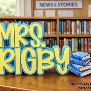 Puede incluir: Un letrero tridimensional con el texto amarillo MRS. RIGBY y un contorno azul claro, colocado junto a una pila de tres libros peque&ntilde;os de color azul con p&aacute;ginas blancas. El letrero se encuentra sobre una superficie de madera frente a una estanter&iacute;a.