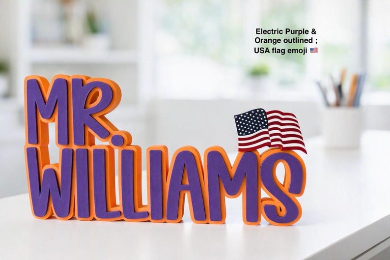 Puede incluir: Un letrero con nombre personalizado que muestra el texto MR. WILLIAMS en letras moradas el&eacute;ctricas en negrita con un borde naranja grueso. Una peque&ntilde;a bandera estadounidense tridimensional est&aacute; unida a la parte superior derecha de la letra S.