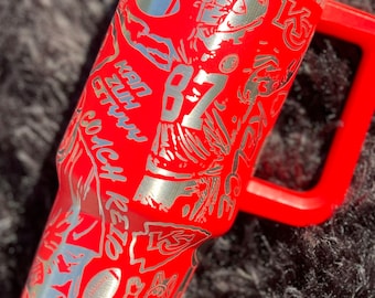 May include: Red stainless steel tumbler with a silver design featuring a football player, the words "Super Bowl Champion", and the number "87".