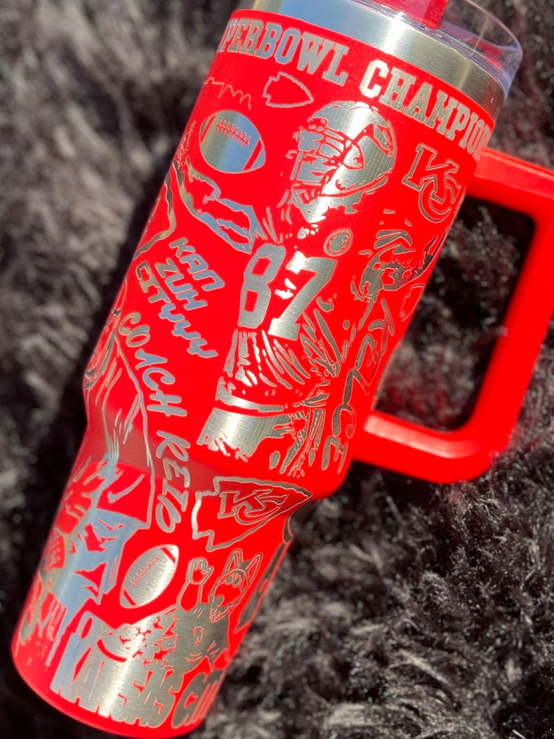 May include: Red stainless steel tumbler with a silver design featuring a football player, the words "Super Bowl Champion", and the number "87".