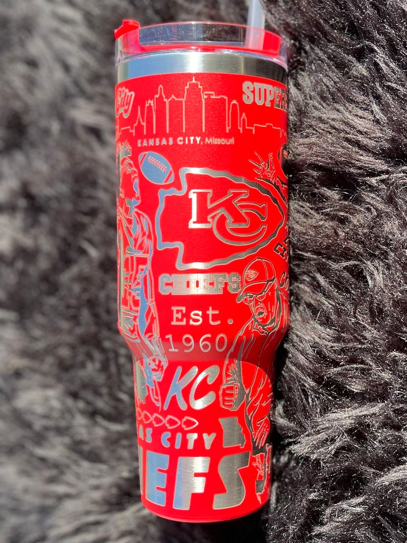 May include: Red stainless steel tumbler with a silver design featuring the Kansas City Chiefs logo, the team's name, and the city skyline. The text "Est. 1960" is also included in the design.