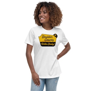 May include: White t-shirt with a yellow and black graphic of a sign that says "Boulder County Roller Derby".