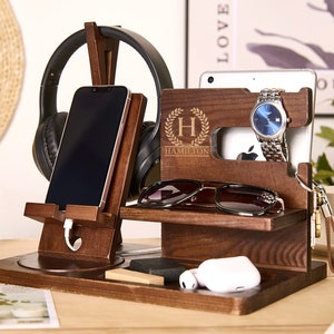May include: A wooden organizer with a phone stand, headphone holder, watch holder, and a small shelf for glasses or keys. The organizer is personalized with the letter "H" and the name "Hamilton".