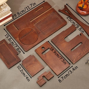May include: Wooden phone stand with multiple compartments for holding phones, watches, and other small items. The stand is made of natural wood and measures 11.7 inches by 7.8 inches.