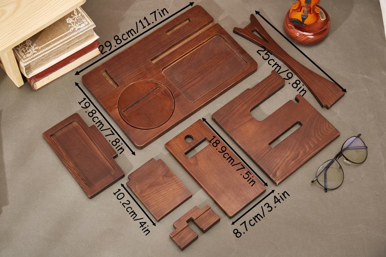 May include: Wooden phone stand with multiple compartments for holding phones, watches, and other small items. The stand is made of natural wood and measures 11.7 inches by 7.8 inches.