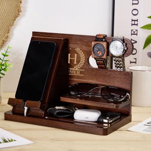 May include: A wooden organiser with a phone stand, watch holders, and a glasses holder. The organiser is personalised with the letter "H" and the name "Homer".