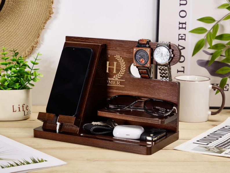 May include: A wooden organiser with a phone stand, watch holders, and a glasses holder. The organiser is personalised with the letter "H" and the name "Homer".