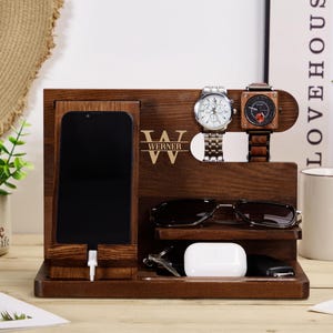 May include: A wooden organiser with a phone charging station, watch holders, and a space for sunglasses. The organiser is personalised with the name "Werner".
