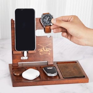 May include: A wooden organizer with a phone stand, watch holder, and compartments for keys and a wallet. The organizer is engraved with the name "Hubert".