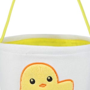 May include: White Easter basket with a yellow chick design. The bucket has a yellow handle and a yellow interior lining. The chick is yellow with an orange outline and orange feet.
