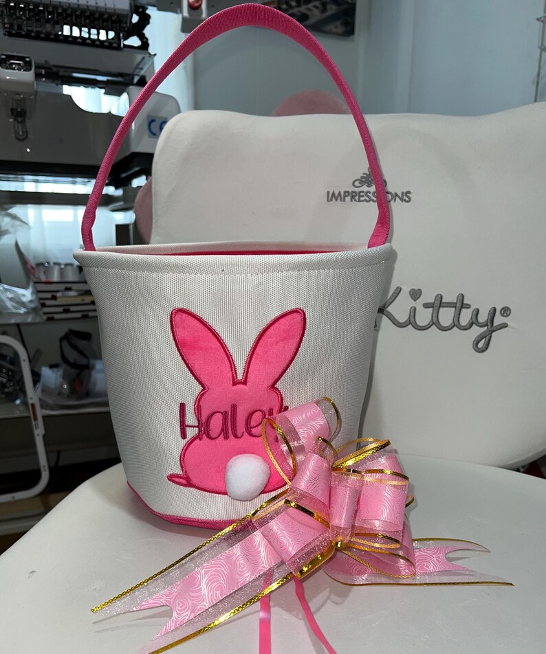 Personalized with buyers choice of name. White canvas Easter Basket with Pink Bunny applique, includes tissue paper, bow and clear gift wrapper