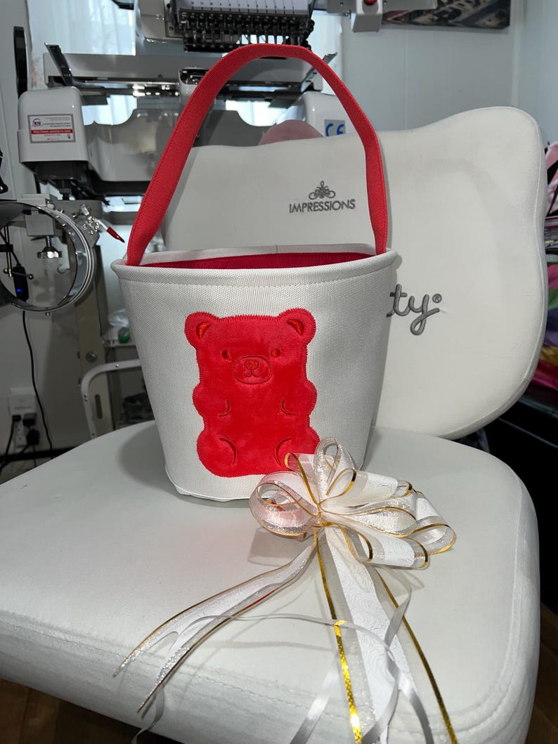Personalized with buyers choice of name. White canvas Easter Basket with Berry Gummy Bear applique, includes tissue paper, bow and clear gift wrapper