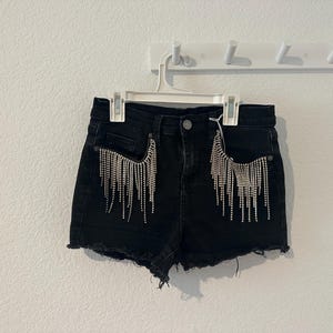 Denim shorts with fringe rhinestone trim on pockets. SIZE 2/26
